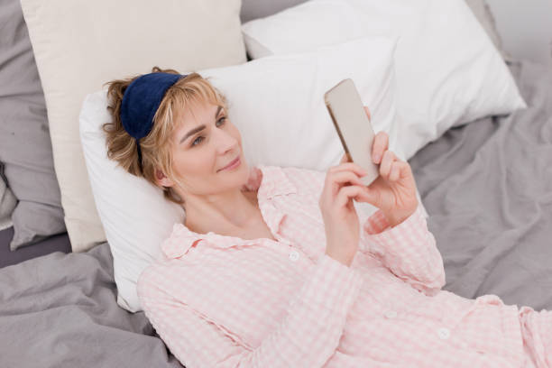 istock Woman holding smartphone and lying bed 2151458466