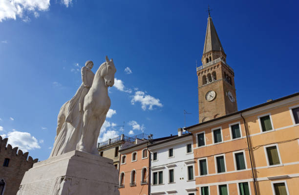 Portogruaro, Italy - April 30, 2018: View of the bell tower of the Duomo di Sant'Andrea and the WWI monument in Piazza della Repubblica, the town's main square