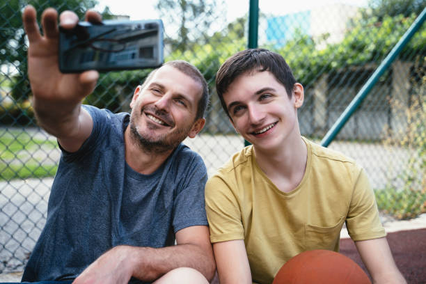 istock Father and son taking a selfie outdoors whilst playing basketball. 2151472519