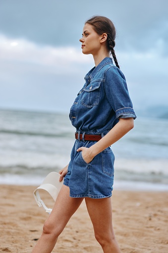 Smiling young woman enjoying summer vacation at the beach - Pretty & Happy Caucasian Model with Attractive Style, Blue Denim & Sun-kissed Hair, Relaxing by the Ocean