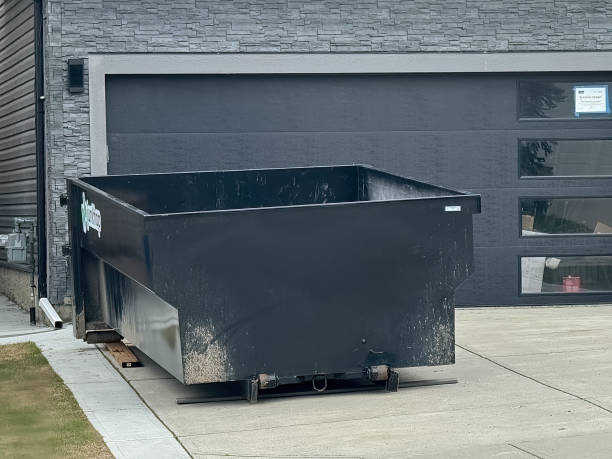 Front view of a black dumpster in front of a house garage. Calgary, Alberta, Canada. May 3, 2024. Front view of a black dumpster in front of a house garage. large dumpster stock pictures, royalty-free photos & images