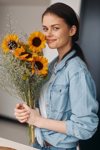 Sun-Kissed Beauty: A Young Caucasian Woman Holding a Bouquet of Yellow Sunflowers Surrounded by Fresh Green Grass and Bright Blue Sky