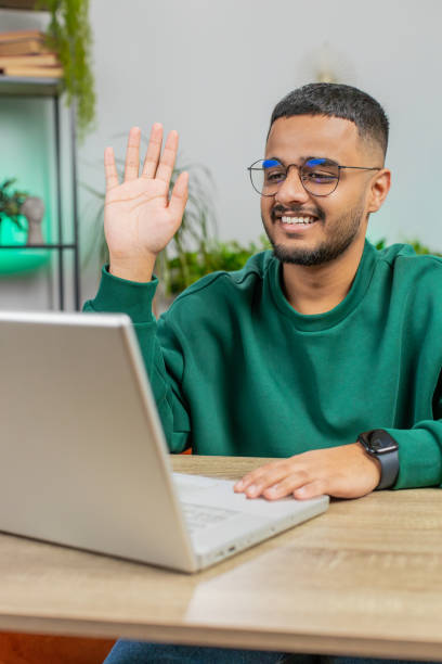 istock Man sitting on home couch, looking at camera, making video conference call with friends or family 2151484314