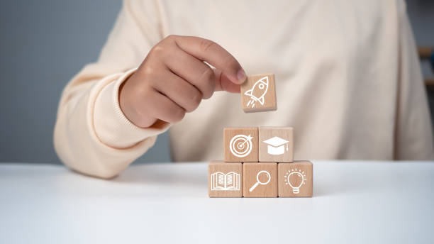 istock Man holding a wooden cube with printed educational symbols, E-learning education, internet lessons and online webinar. Education internet Technology. Success and necessary skills in graduation. 2151494382