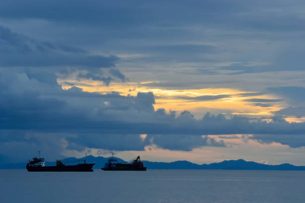 Scenery image of cargo vessels mooring at the sea, under the sunset sky.