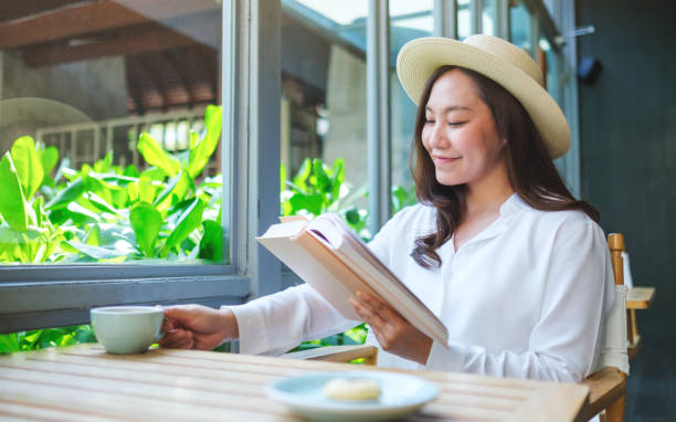 istock Portrait image of a beautiful young woman with hat drinking coffee while reading book 2151509168