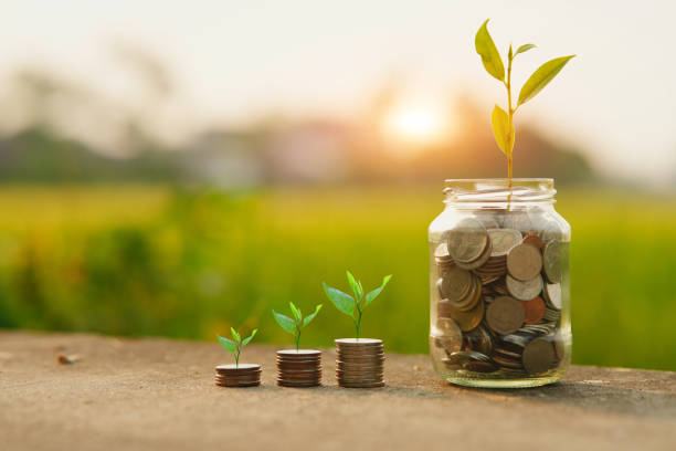 istock Saving money by hand puting coins in jug glass on nature background 2151514652