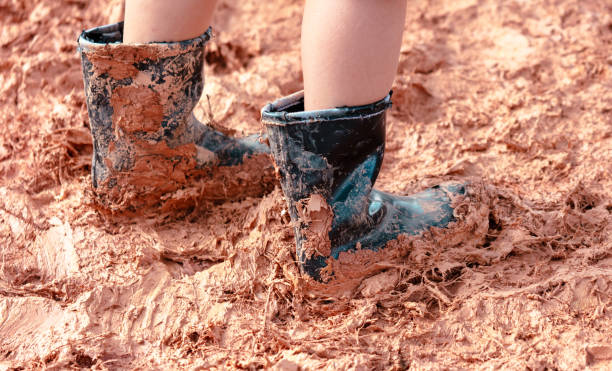 A man in rubber boots walks on clay.