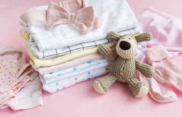 istock Baby  crocketed toy of dog  next to a stack rompers for kids 2151516925