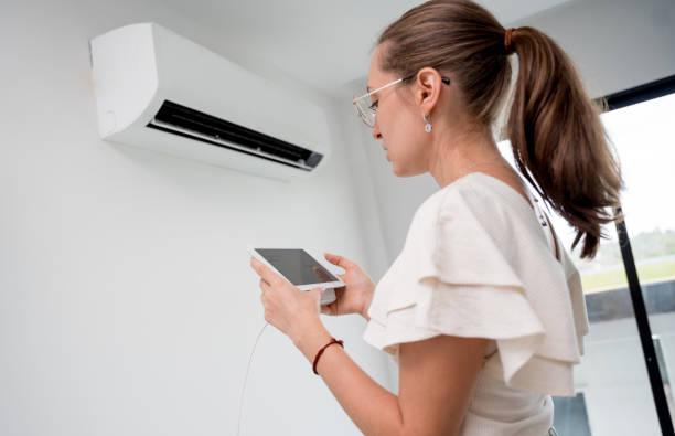 istock Young woman operates wireless aircon system in a modern apartment. 2151517496