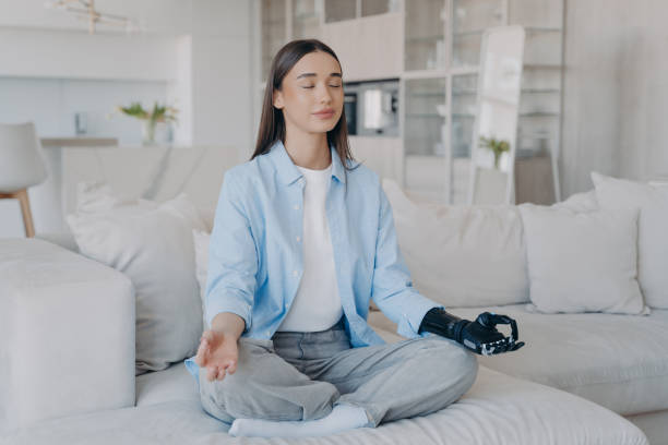 Serene woman with robotic arm meditates on couch, blending tranquility with modern tech.