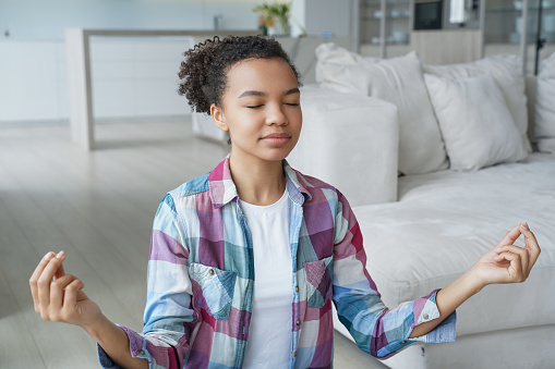 Peaceful young person practicing meditation, finding balance in a serene home setting.
