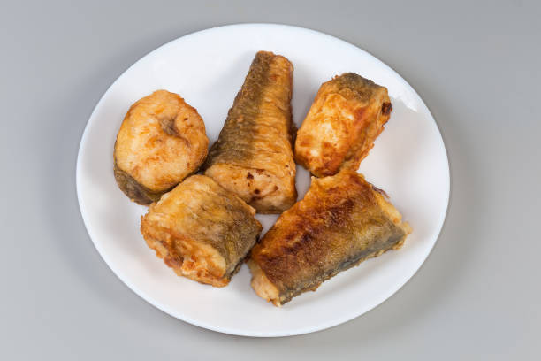 Fried pieces of hake hubbsi, or Argentine hake on white dish on a gray background