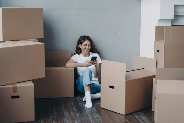 istock Cheerful woman enjoying a message on her phone among unpacked moving boxes. 2151526870