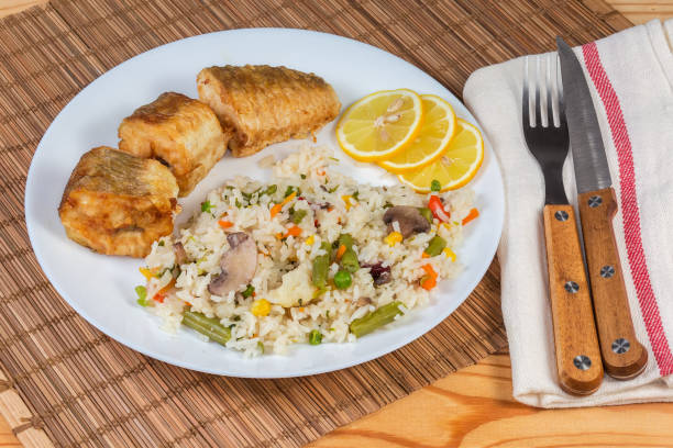 istock Serving of fried hake hubbsi pieces with rice and vegetables 2151526970