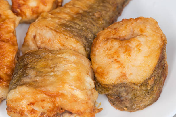 Fried pieces of hake hubbsi, or Argentine hake on white dish, fragment close-up in selective focus