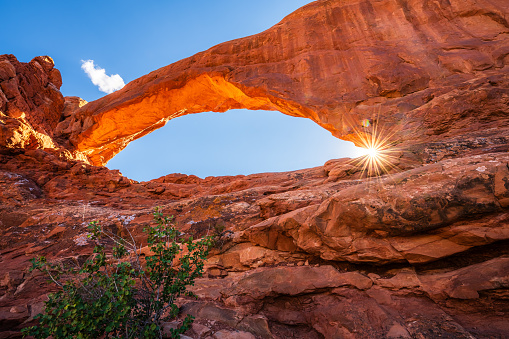 The sun star shining through the North Window Arch in the Arches National Park in the Moab, Utah, USA.
