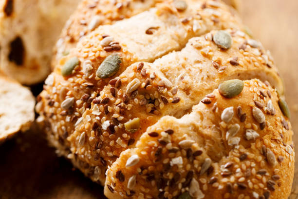 Homemade sliced bread with crispy crust and seeds on wooden table background.