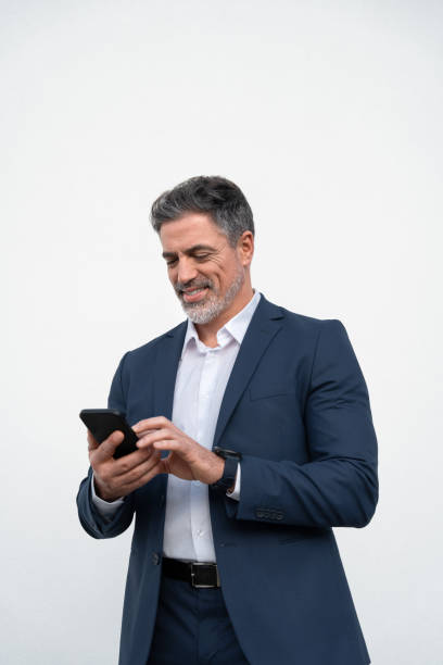 Mature businessman in suit holding cellphone isolated, white background. Smiling 40s Latin business man using smartphone mobile phone screen device, scrolling app, working for communication. Vertical hombre de negocios maduro en traje sosteniendo teléfono celular aislado, fondo blanco. hombre de negocios latino sonriente de los años 40 usando un dispositivo de pantalla de teléfono móvil inteligente, aplicación de desplazamiento, trabajando para la