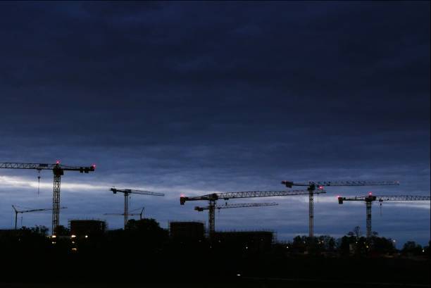 Tall red tower crane and colorful metal structures at construction equipment yard