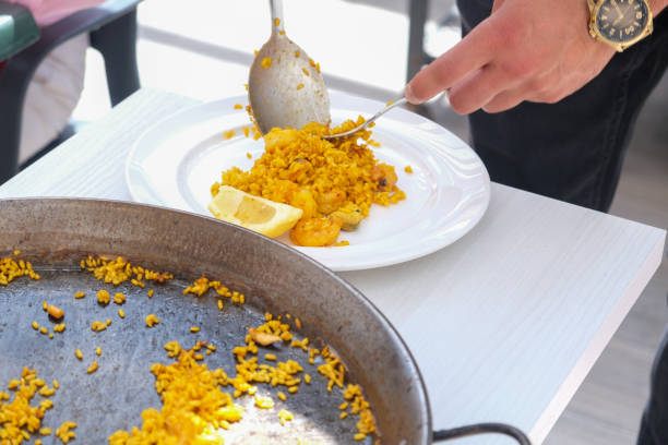 The waiter serves the Spanish national dish paella.
