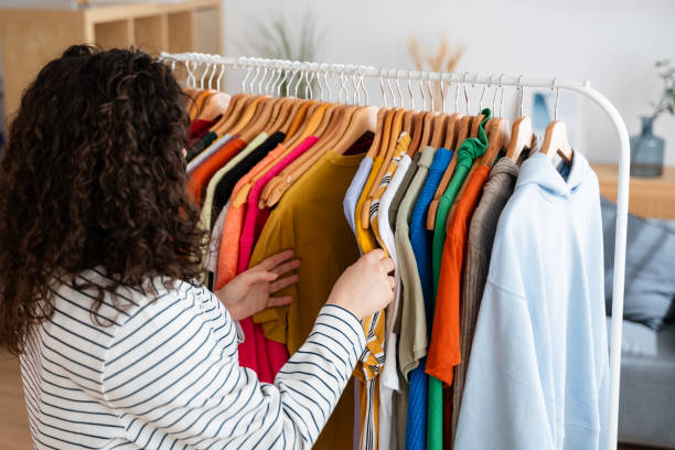 istock Woman browsing through colorful clothing on rack 2151538899