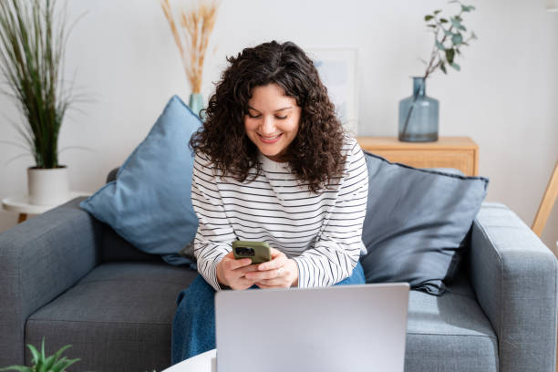 istock Smiling woman using smartphone on couch 2151539027