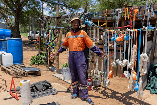 african street vendor selling hardware on the side of the road, wearing orange workwear and dreadlocks braids