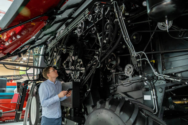 Serviceman with digital tablet on a next to combine harvester