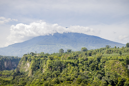 View over a valley to a mountain in tropical surroundings. The picture is taken in Bukittinggi in the northwestern part of Sumatra