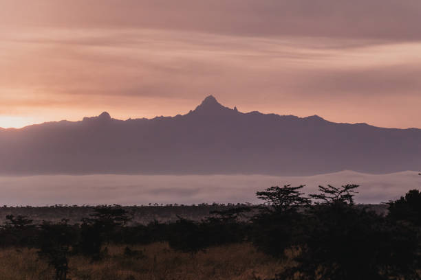 Fiery sunset silhouettes Mount Kenya over misty landscape