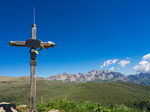Mountain summit cross with Dolomites in background