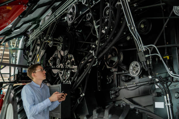 istock Serviceman with digital tablet on a next to combine harvester 2151550057
