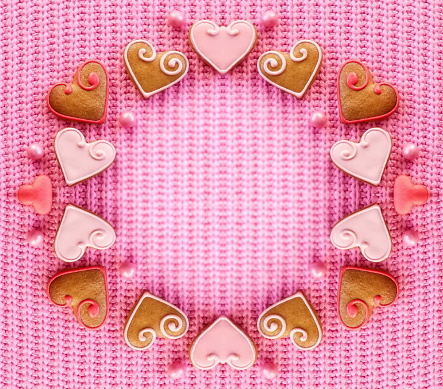 Top view of a cute gingerbread cookies in a Valentine's day frame. The cookies are placed on a pink background and there is ample copy space available
