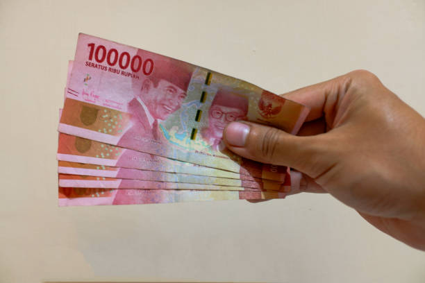 istock Man's Hand showing rupiah money isolates on cream background 2151551525