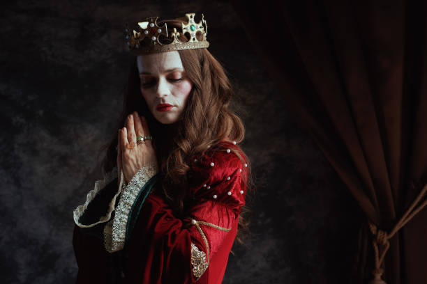 istock medieval queen in red dress with crown praying 2151557645