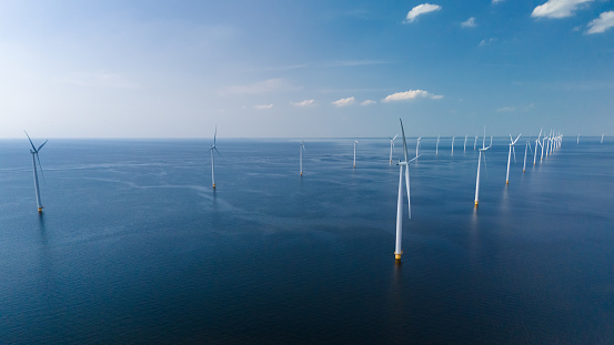 A group of wind turbines, sleek and modern, dance gracefully on the ocean waves, harnessing the power of the wind in Flevoland, Netherlands.