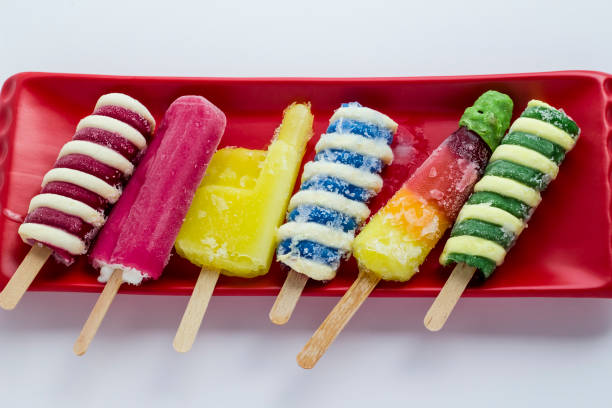 Above view of colorful,frozen stick ice creams on the red long plate on white surface