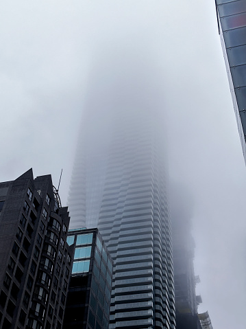 A tall apartment building in downtown Toronto  shrouded in the mist of a rainy grey day