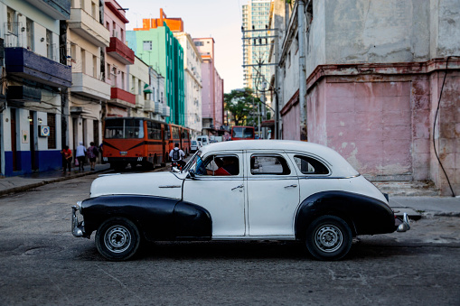 An old car, restored and repainted, driving along a street in Havana