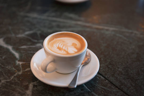 istock Elegant Cappuccino with Leaf Pattern Latte Art on Marble Cafe Table 2151571409