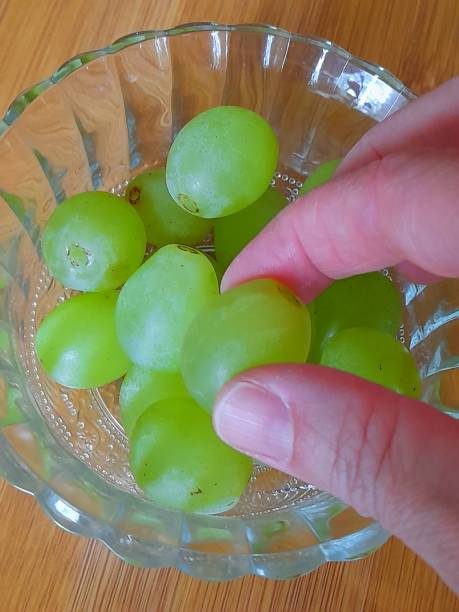 istock Grape seeds in glass bowl with hand. 2151572371