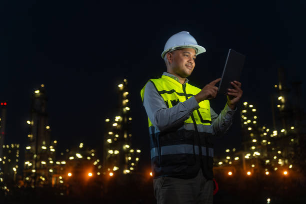 istock Night scene. Happy handsome Asian man petrochemical engineer working with digital tablet. He going through routine checks at petroleum oil refinery in industrial estate. 2151572526