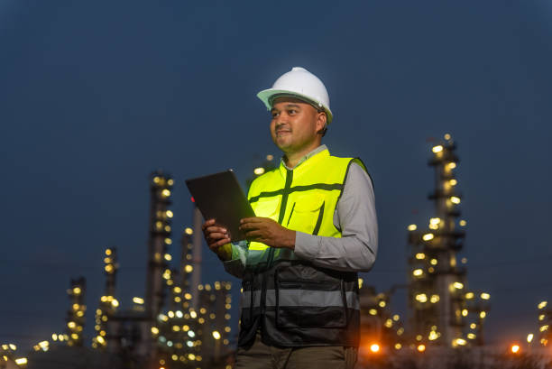 istock Night scene. Happy handsome Asian man petrochemical engineer working with digital tablet. He going through routine checks at petroleum oil refinery in industrial estate. 2151572527