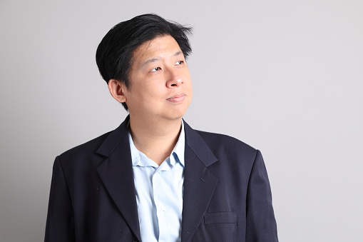 The Asian Businessman with formal dressed with gesture of standing on the gray background.