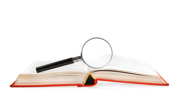 istock open book in a red hardcover with a magnifying glass on a white background. learning concept 2151574999