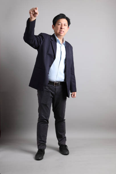 The Asian Businessman with formal dressed with gesture of pointing on the gray background.