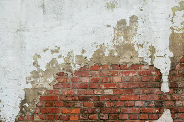 istock An ancient red brick wall, partially covered with gray plaster. Background. There is space for text. 2151590017
