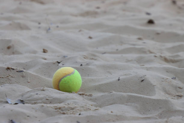 istock Isolated beach tennis ball in the sand with copy space 2151591896