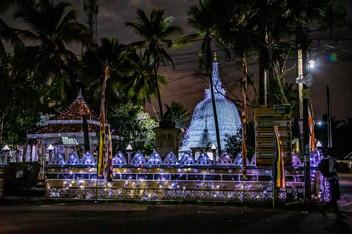 Kalutara, Sri Lanka , 10.02.2023 traditional Sri Lankan white temple stupa illuminated with lights in the evening. festively decorated stupa